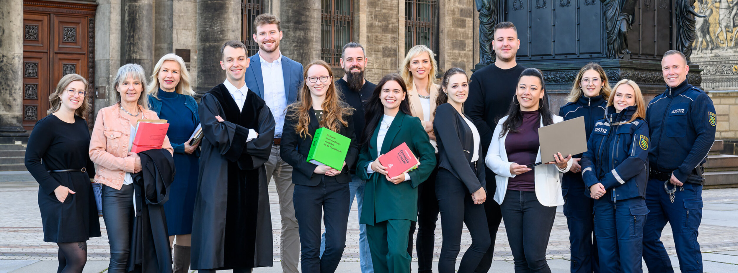 Eine Gruppe von Mitarbeitern verschiedender Fachgebiete beim Gericht steht vor dem Gerichtsgebäude