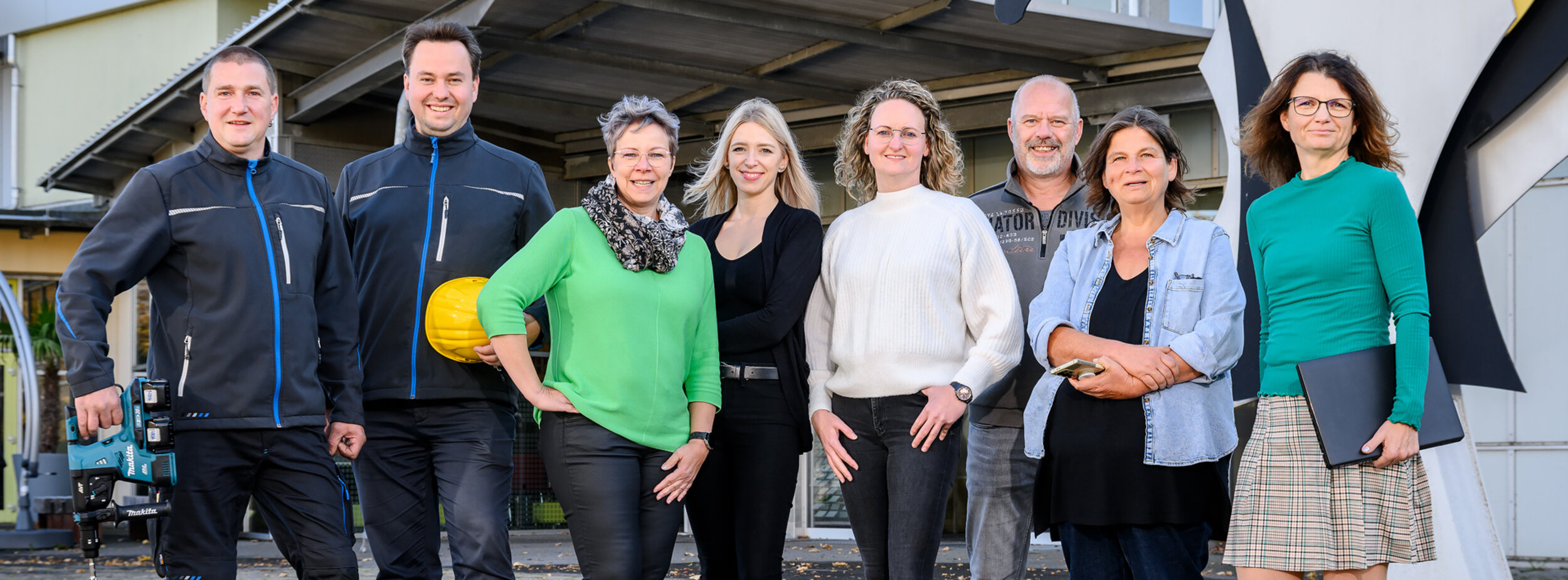 Mitarbeiter des Ausbildungszentrums stehen vor dem Eingang des Ausbildungszentrums