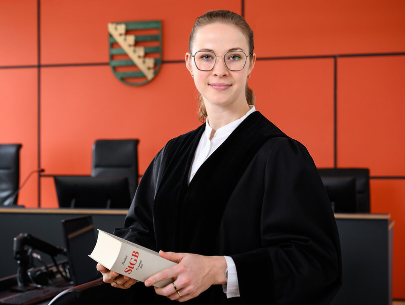 Eine junge Staatsanwältin im Gerichtssaal mit einem Gesetzbuch in der Hand
